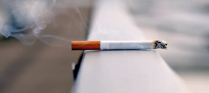 Une personne jette une cigarette dans une poubelle, symbolisant l'acte d'arrêter de fumer pour protéger la santé cardiovasculaire.