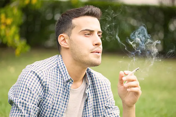 Un bureau de travail avec une cigarette écrasée sur un cendrier plein, symbolisant les risques professionnels liés au tabagisme.